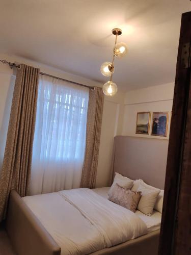 a bedroom with a bed with a window and a chandelier at Zoe Homes Oak Villa Apartment 1 and 2 Bedroom 201 in Kericho