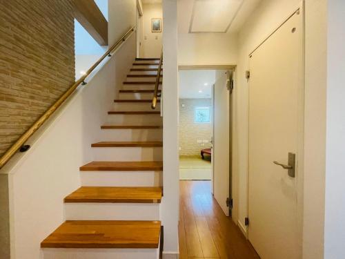 a staircase in a house with white walls and wooden floors at 空港まで車で15分ビーチまで徒歩1分海沿いの閒雲斎 in Itoman