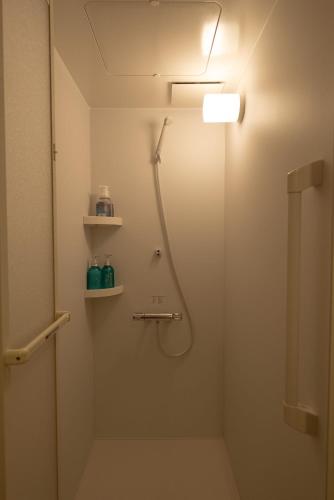a bathroom with a shower with a light on the wall at 空港まで車で15分ビーチまで徒歩1分海沿いの閒雲斎 in Itoman