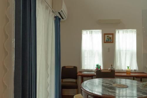 a living room with a table and a dining room at 空港まで車で15分ビーチまで徒歩1分海沿いの閒雲斎 in Itoman