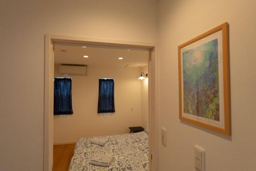 um quarto com uma cama e um quadro na parede em 空港まで車で15分ビーチまで徒歩1分海沿いの閒雲斎 em Itoman
