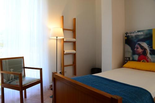 a bedroom with a bed and a chair and a window at Caparica Sun Centre in Costa da Caparica