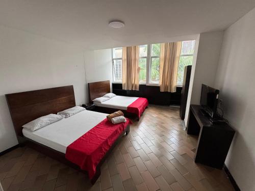 a bedroom with two beds and a flat screen tv at Hotel Catalina Plaza Pereira in Pereira