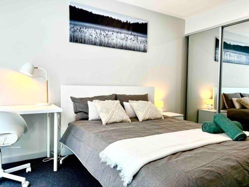 a bedroom with a bed with a desk and a picture on the wall at Brand new 1 bedroom apartment in Canberra Centre in Canberra