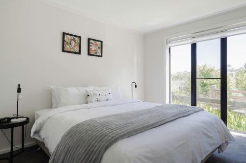 ein weißes Schlafzimmer mit einem Bett und einem großen Fenster in der Unterkunft The Cottage at Oak Tree Farm - Vineyards & Wildlife in Hastings