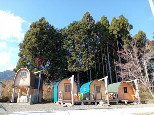a group of tiny homes parked in front of trees at Star Forest Makino Glamping Villa in Takashima