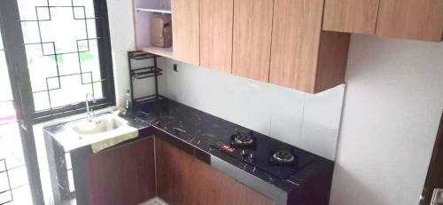 a kitchen with wooden cabinets and a sink at Rumah 5KT Sby Brt dkt Kidzania in Surabaya