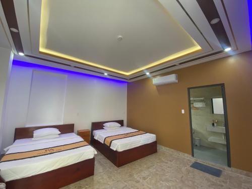 two beds in a room with a large ceiling at Phi Anh Hotel in Bình Minh