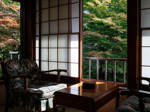 a room with a chair and a table and windows at Chousenkaku Kameya in Shimo-suwa