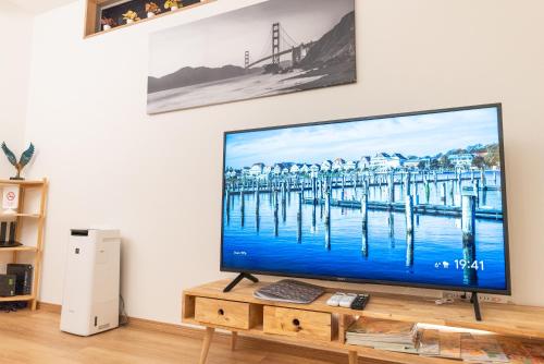 a flat screen tv sitting on top of a wooden table at Guest House Kubo Homes Tenjin Dori in Osaka