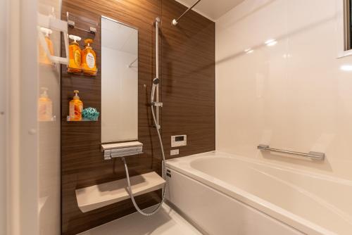 a bathroom with a white tub and a sink at Guest House Kubo Homes Tenjin Dori in Osaka