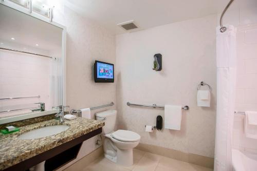 a bathroom with a toilet and a sink and a tv at Renaissance Raleigh North Hills Hotel in Raleigh