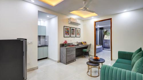 a living room with a green couch and a kitchen at 1BHK Suites Opp Marriott - Huda City Centre in Gurgaon