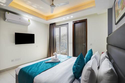 a bedroom with a bed with blue pillows and a tv at 1BHK Suites Opp Marriott - Huda City Centre in Gurgaon