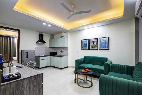 a living room with two green couches and a kitchen at 1BHK Suites Opp Marriott - Huda City Centre in Gurgaon