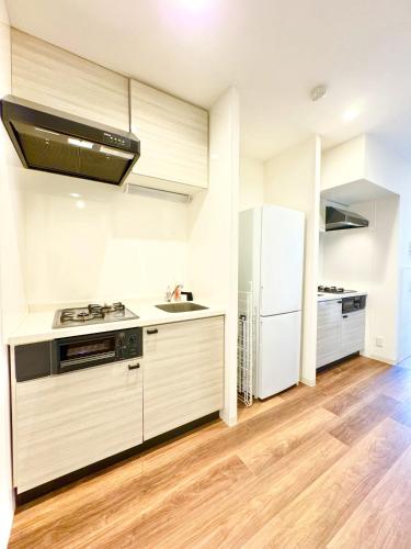 a kitchen with white appliances and a refrigerator at ansok青井 一軒家を改装した清潔なホステル 個室 in Tokyo