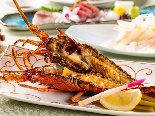 a plate of lobster on a table with other plates of food at 公共の宿伊豆まつざき荘 in Matsuzaki