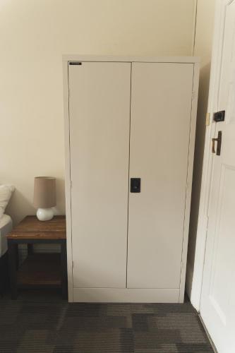 a white cabinet in a room with a table at Manly Bunkhouse in Sydney