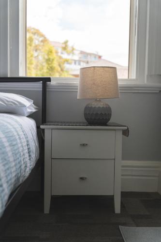 a lamp on a night stand next to a bed at Manly Bunkhouse in Sydney