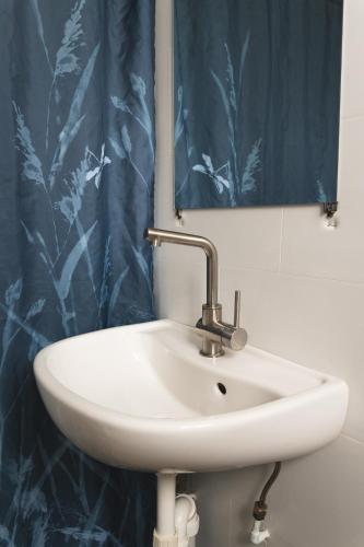 a white sink in a bathroom with a blue shower curtain at Manly Bunkhouse in Sydney