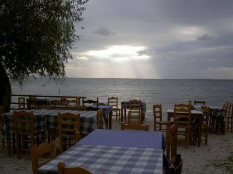 a group of tables and chairs on the beach at Apartments Zoumperi in Nea Makri