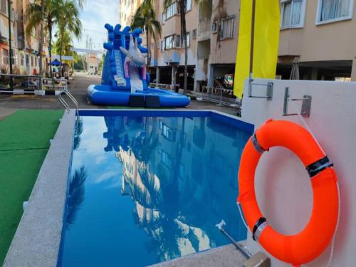 a pool at a resort with an orange life preserver at Capital O 91107 Pd Tiara By Delima Suites in Kampong Batu Empat Belas