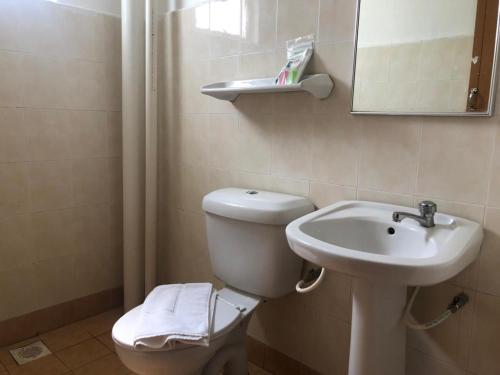 a bathroom with a toilet and a sink and a mirror at Capital O 91107 Pd Tiara By Delima Suites in Kampong Batu Empat Belas