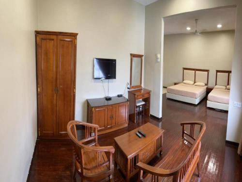 a living room with a table and chairs and a bed at Capital O 91107 Pd Tiara By Delima Suites in Kampong Batu Empat Belas