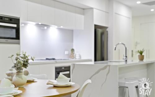 a white kitchen with a table and a sink at Ruby - 2 Bedroom Penthouse in Surfers Paradise! in Gold Coast