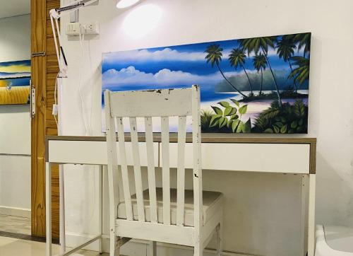 a white desk with a chair and a painting on the wall at Malai Maikhao Near Beach in Ban Mai Salae