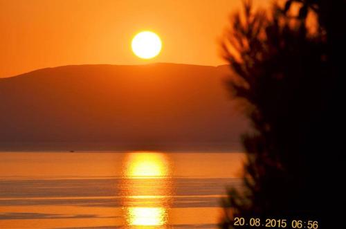 a sunset over a body of water with a mountain at Apartments Zoumperi in Nea Makri