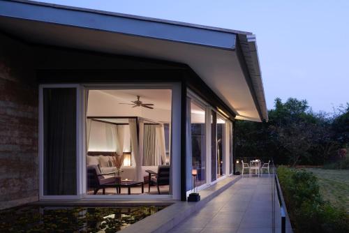 a glass extension of a house with a patio at Dharana at Shillim All Inclusive Luxury Wellness Retreat in Lonavala