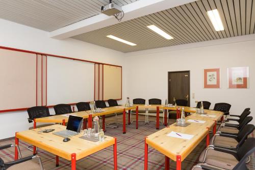 a conference room with tables and chairs and a laptop at Hotel Alpenhof Postillion in Kochel