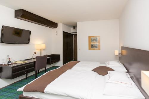 a hotel room with a large bed and a desk at Hotel Alpenhof Postillion in Kochel