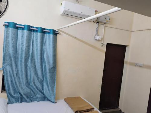 蒂鲁奇奇拉帕利Thiruveesar SVK Homestay的床上的蓝色窗帘