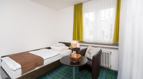a bedroom with a bed and a table and a window at Hotel Alpenhof Postillion in Kochel