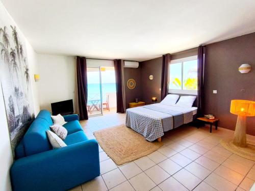 a living room with a blue couch and a bed at Le Caro - pieds dans l'eau - clim - wifi in Saint-Gilles-les-Bains