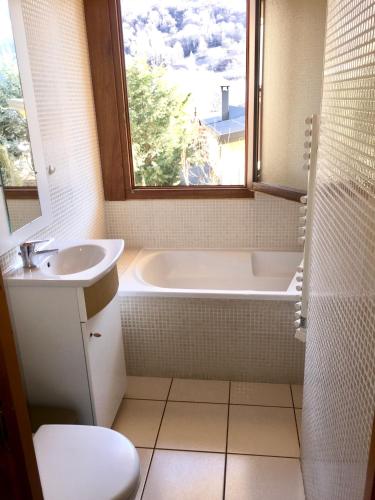 une salle de bain avec une baignoire, un lavabo et une fenêtre dans l'établissement Appartement vue sur les pistes, à Valloire