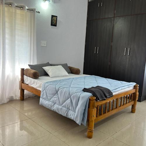 a bedroom with a bed with a blue blanket and cabinets at Sri Krishna AC Homestay in Udupi