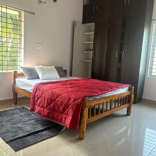 a bedroom with a bed with a red blanket at Sri Krishna AC Homestay in Udupi