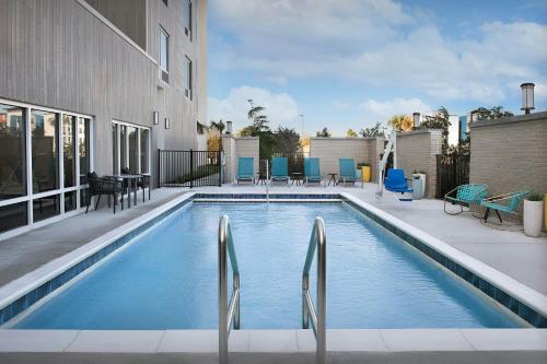 a swimming pool with blue chairs and a building at TownePlace Suites by Marriott Fort Myers Gulf Coast in Fort Myers