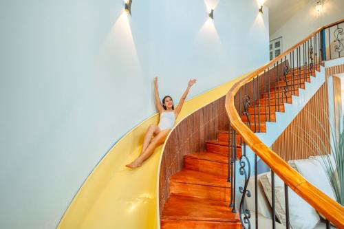 a woman is sitting on the stairs of a house at Cozy Wild in Ban Kai Noi