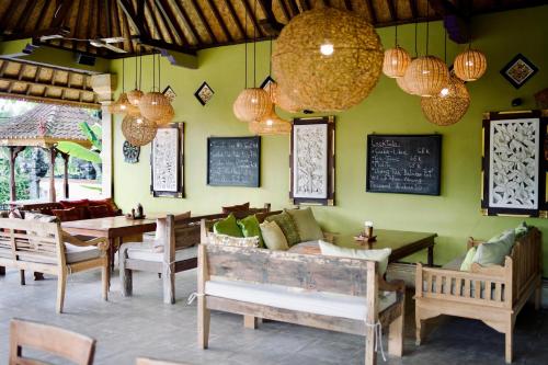a restaurant with a couch and tables and chairs at Abian Bali Resort Amed in Amed