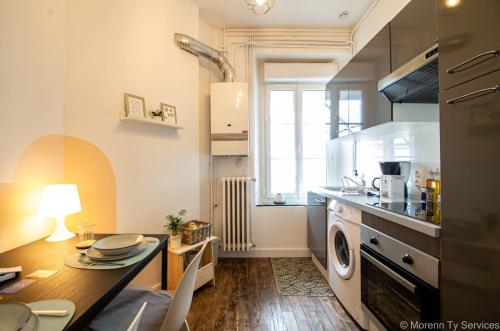 une cuisine avec une table et une cuisinière four supérieur dans l'établissement T1 Odorico proche gare - Ty Artiste Colombia, à Rennes