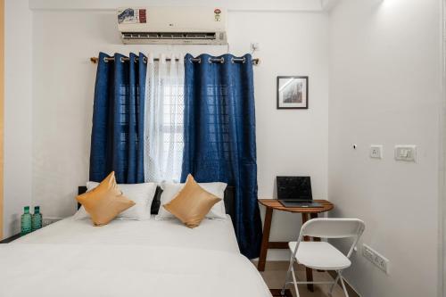 Un dormitorio con una cama con cortinas azules y un escritorio. en Grand suite Susan homestay 302, en Bangalore