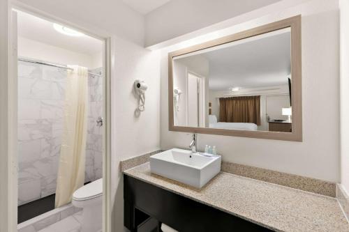a white bathroom with a sink and a mirror at Clarion Pointe Kennesaw Town Center in Kennesaw