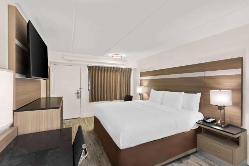 a hotel room with a large bed and a television at Clarion Pointe Kennesaw Town Center in Kennesaw