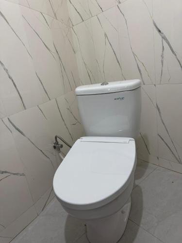 a white toilet in a bathroom with marble walls at Pinggan Cliff in Baturaja