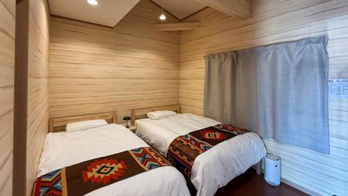 two beds in a room with wooden walls at Sol Stay Osaka 桜シーズン特惠 in Osaka