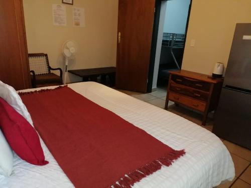 a bedroom with a bed with a red blanket on it at Ebenhaeser overnight accomodation in Bela-Bela
